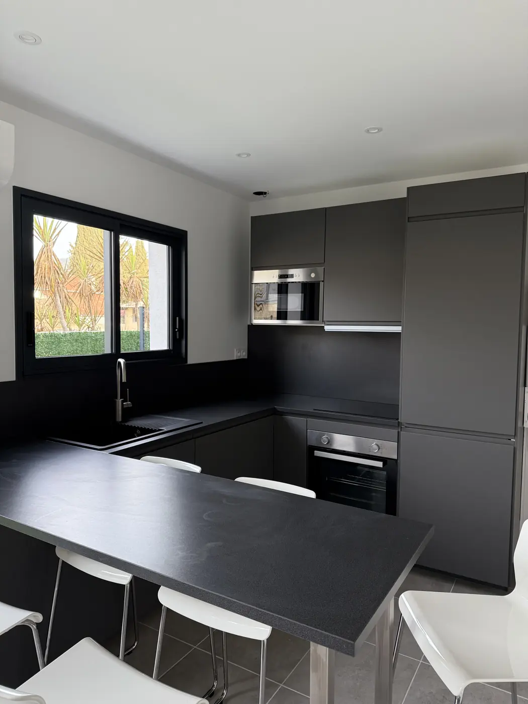 Cuisine noire équipée avec four, micro-ondes et bar