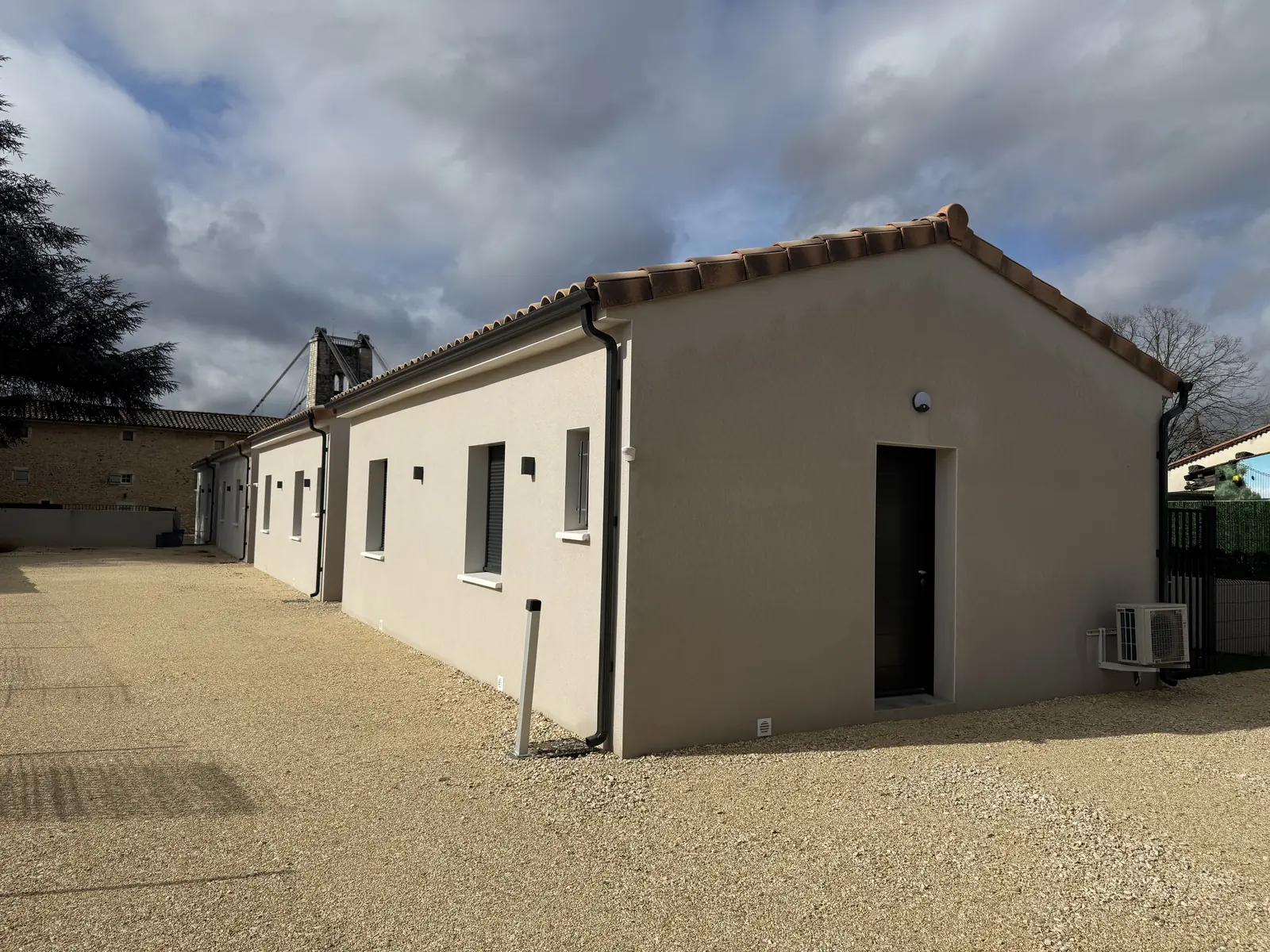 Façade des gîtes et cour gravillonnée servant de parking