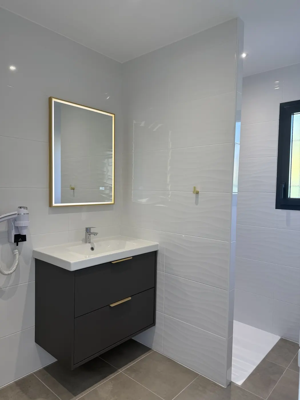 Salle d’eau avec vasque, miroir lumineux et douche à l’italienne