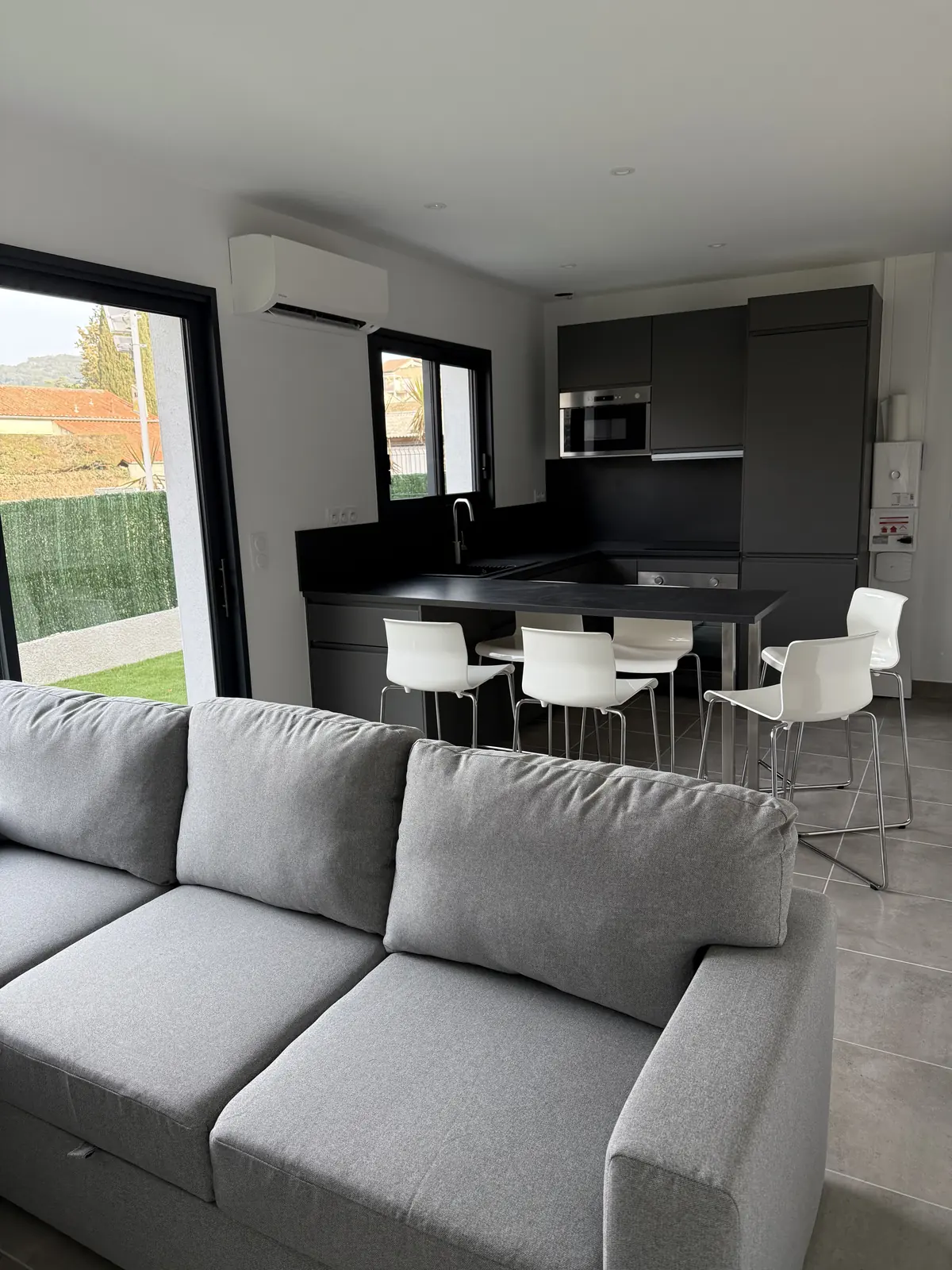Salon avec canapé ouvert sur la cuisine et le bar