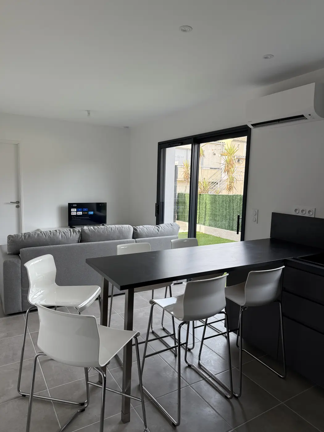 Pièce à vivre avec table haute, canapé et baie vitrée