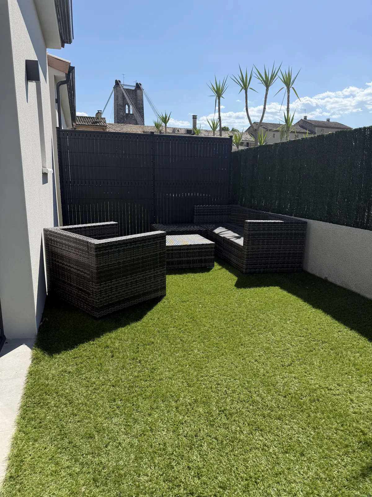 Terrasse privée avec salon de jardin, la tour du pont suspendu visible au-dessus des toits